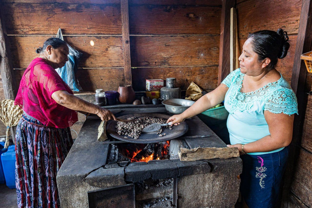 Zwei Frauen in Guatemala bei der traditionellen Kakao-Herstellung über offenem Holzfeuer – authentisches Handwerk und faire Lieferkette